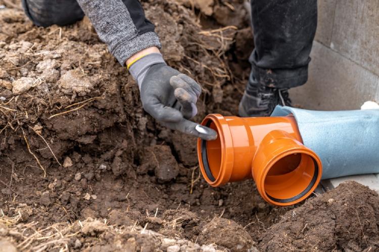 A plumber pointing into a 4” sewer pipe