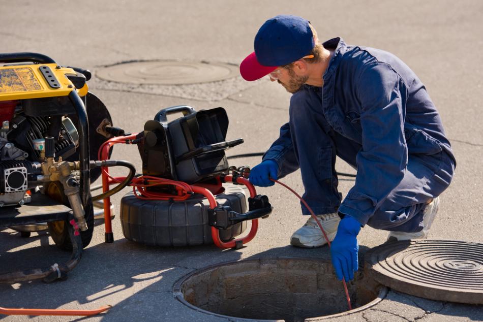A plumber putting a camera down a sewer